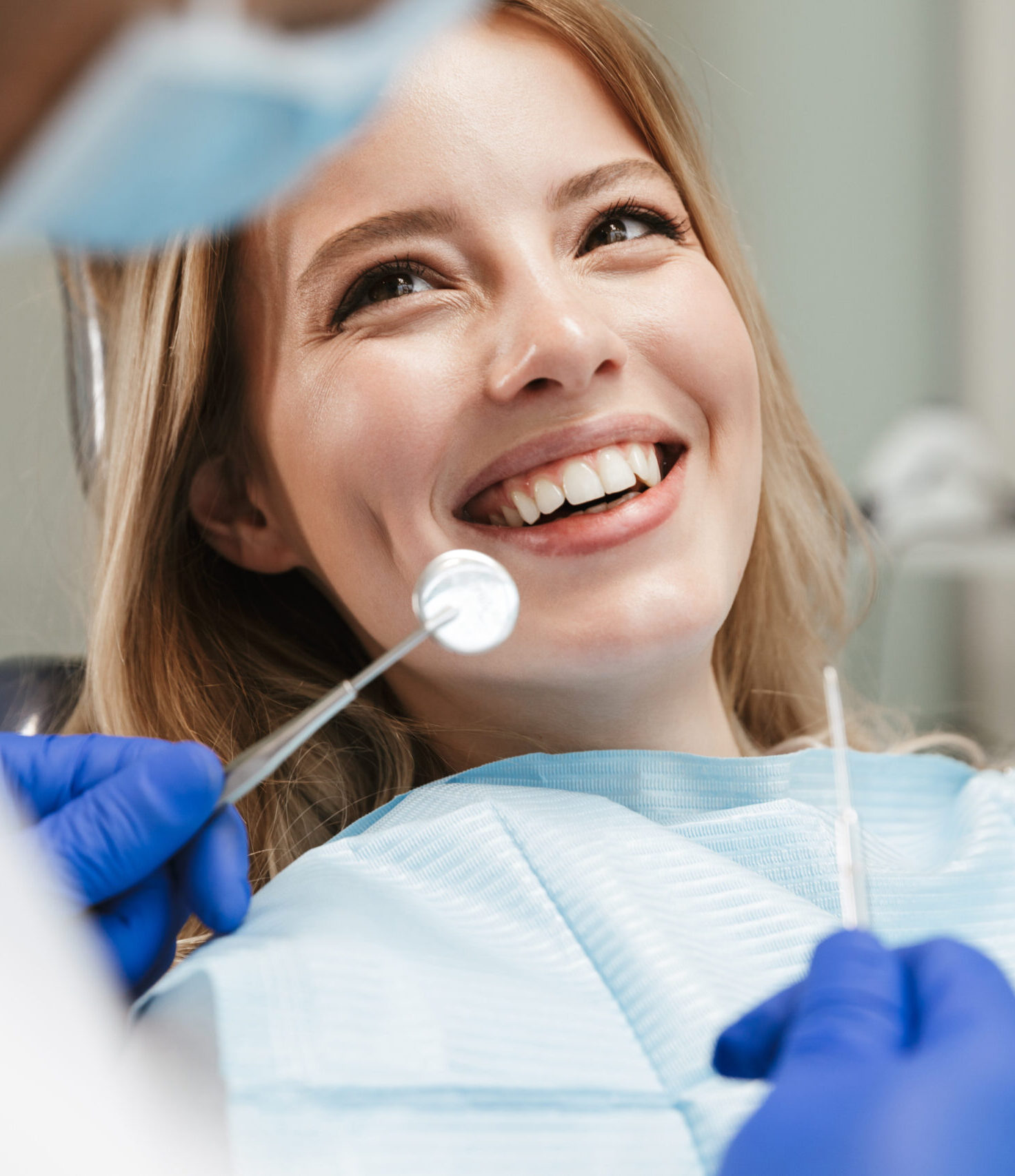 Image of pretty young woman sitting in dental chair at medical center while professional doctor fixing her teeth