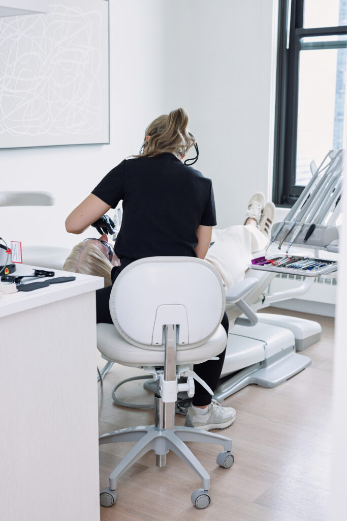 Young woman admiring her smile in a mirror at a dental office