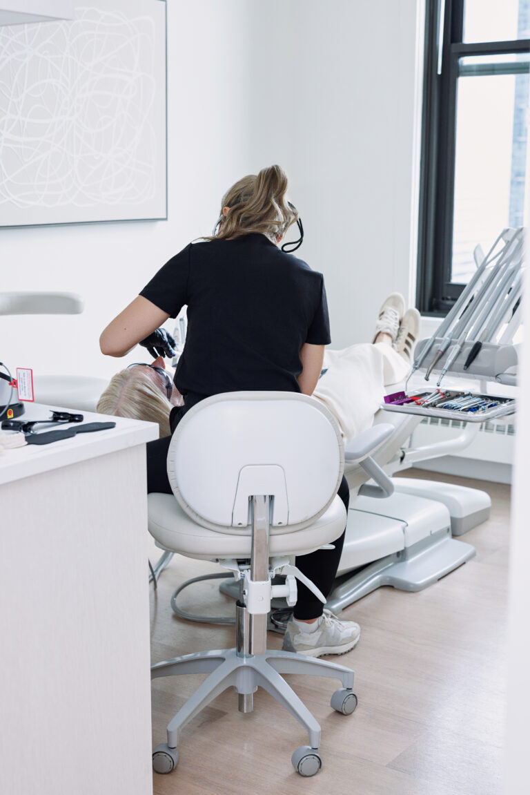 Young woman admiring her smile in a mirror at a dental office