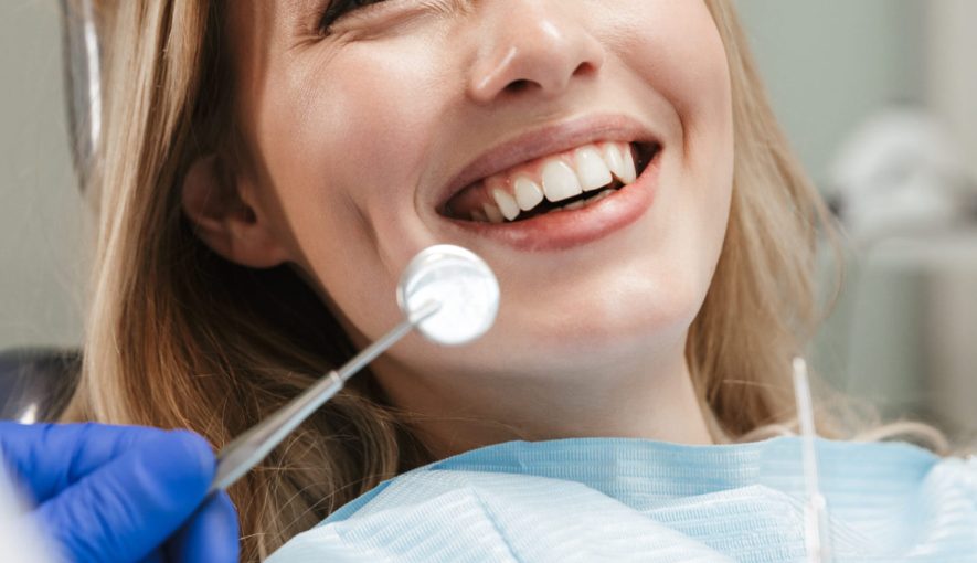 Image of pretty young woman sitting in dental chair at medical center while professional doctor fixing her teeth