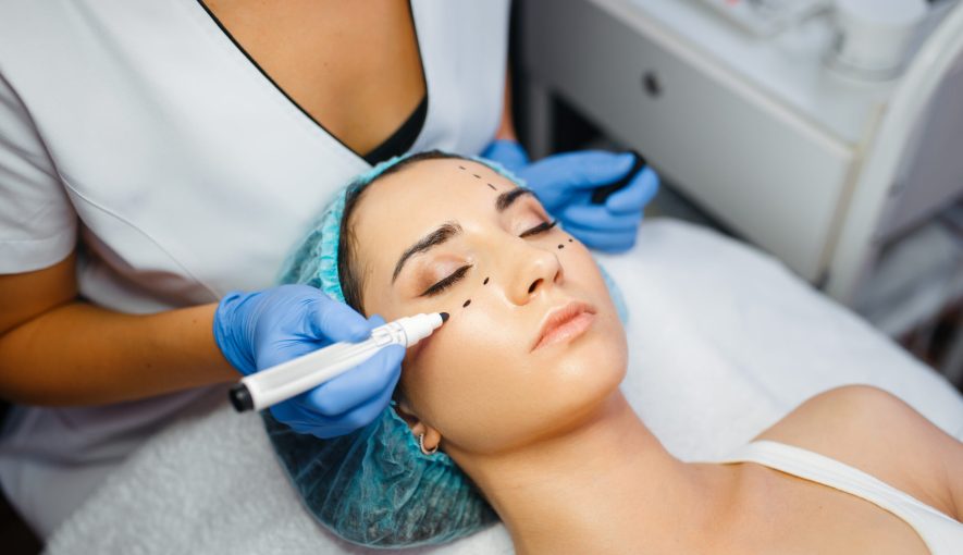 Cosmetician with marker puts dotted lines on female patient face, botox injections preparation. Rejuvenation procedure in beautician salon. Cosmetic surgery against wrinkles and aging