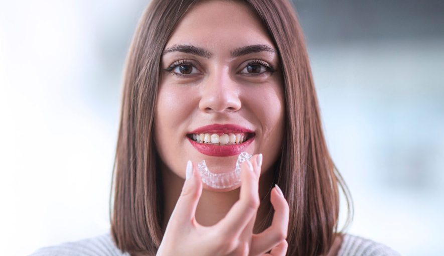 Beautiful smiling Turkish woman is holding an invisalign bracer, includes copy space
