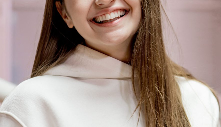 Happy smiling young woman with snow-white smile at dentist reception. Dental care concept.